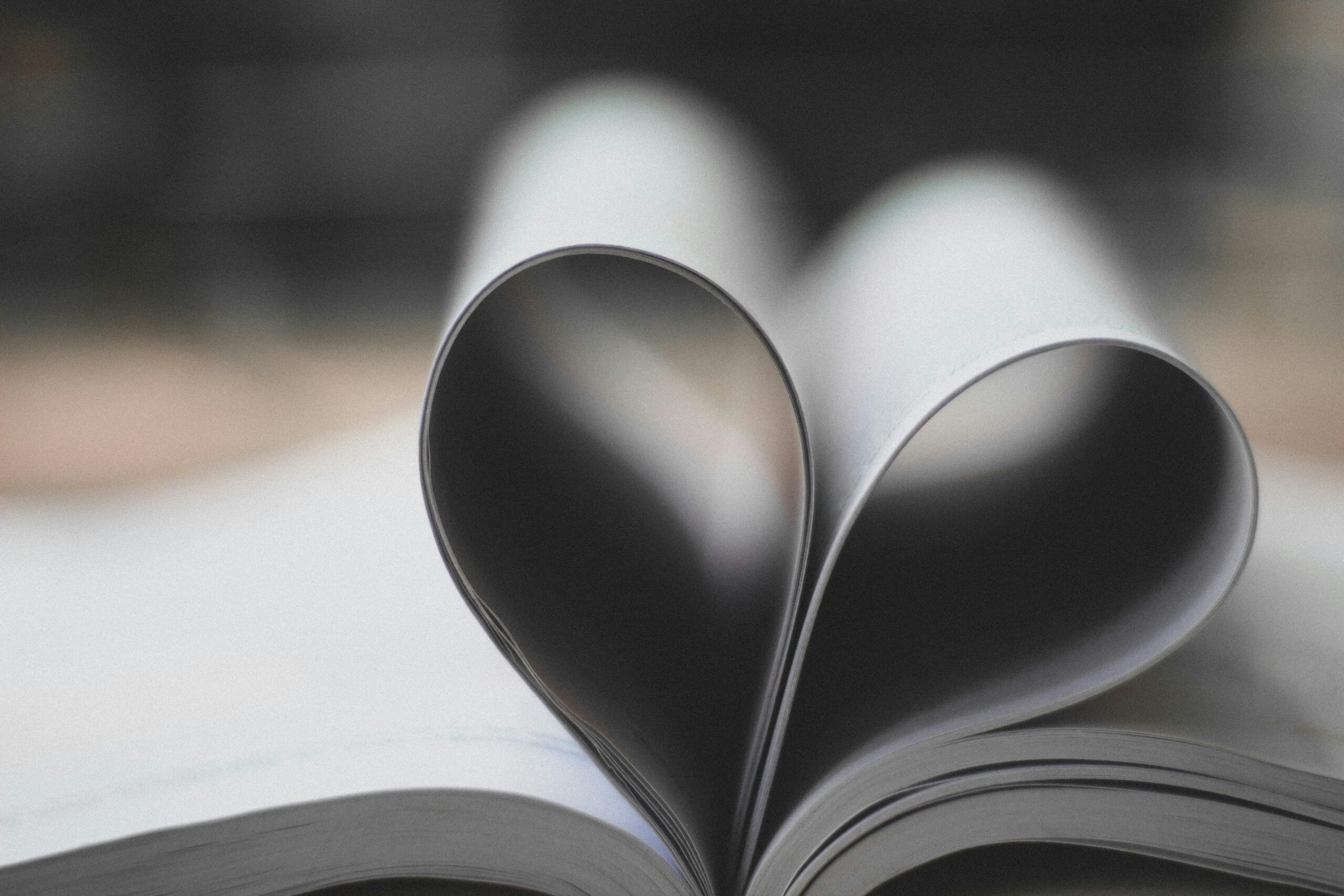 Open book pages forming a heart shape, symbolizing love and creativity.